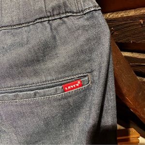 Levi’s jeans with elastic waistband, tapered legs, and utility buckle closure.